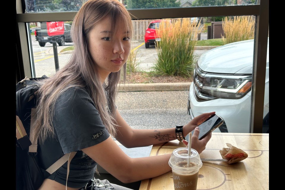 Grade 12 student Veronica Tu scrolls on her phone at Tim Hortons.