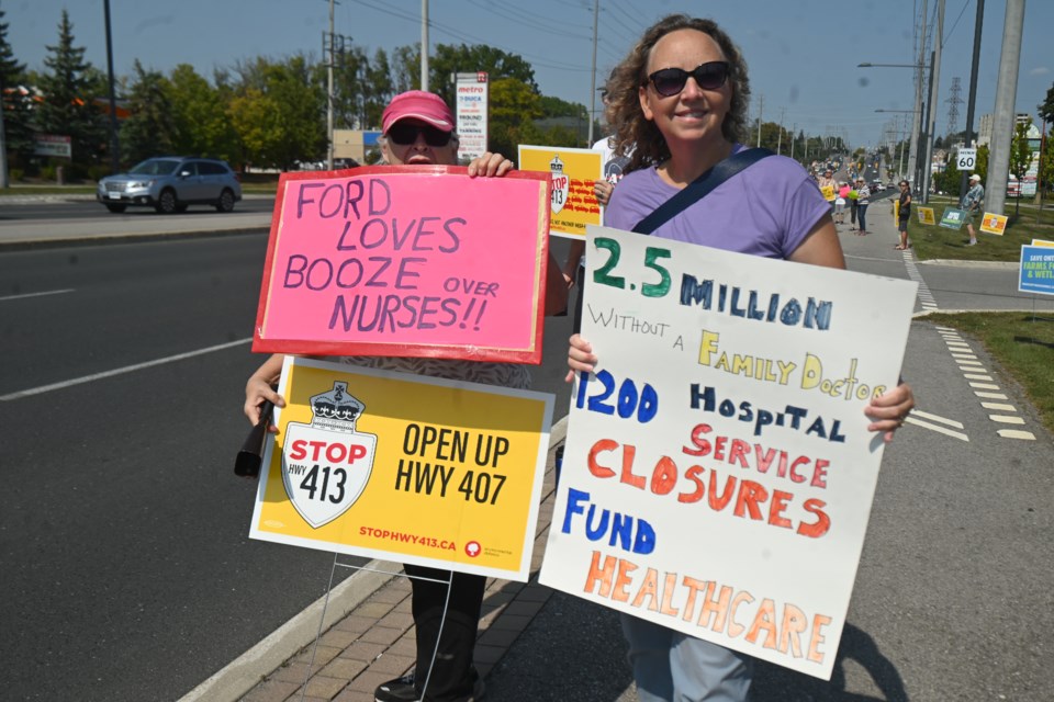 Gloria Reszler and Kelly Dunn hold signs for a rally regarding the Bradford Bypass and Highway 413 in Newmarket Sept. 14. 