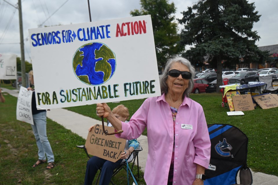 Organizer Janice Berger holds up a sign at Yonge Street and Mulock Drive for a Seniors for Climate Action Now rally. 