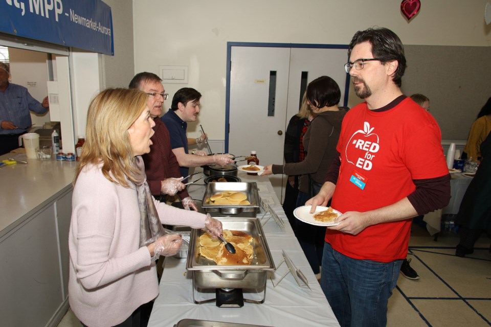 Newmarket-Aurora MPP Christine Elliott serves pancakes to Newmarket elementary school teacher Chris Fuerth at a Feb. 29 pancake breakfast held for residents at St. Andrew's Presbyterian Church hall.  Greg King for NewmarketToday