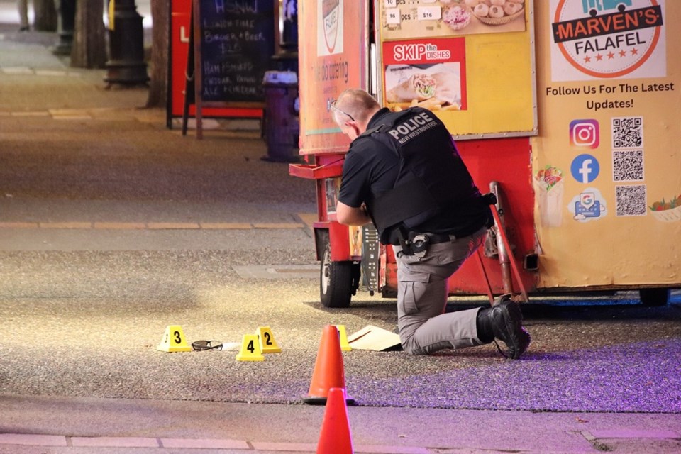 An investigator with the New Westminster Police Department (NWPD) examines evidence at the scene of a double stabbing on Columbia Street near the SkyTrain Station the night of Oct. 11, 2024.