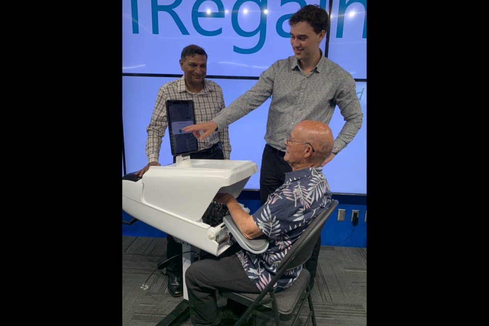 Eric Dumais (pointing), IRegained's clinical research lead, guides David Leblanc on the use of MyHand, while Vineet Johnson, IRegained's president and CEO, looks on.