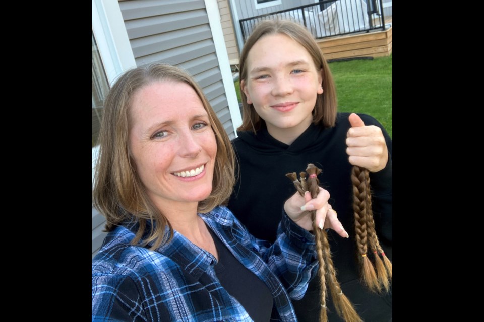 Amanda Fretz and her daughter Samantha hold up the ponytails they are donating to the charity Angel Hair for Kids. 