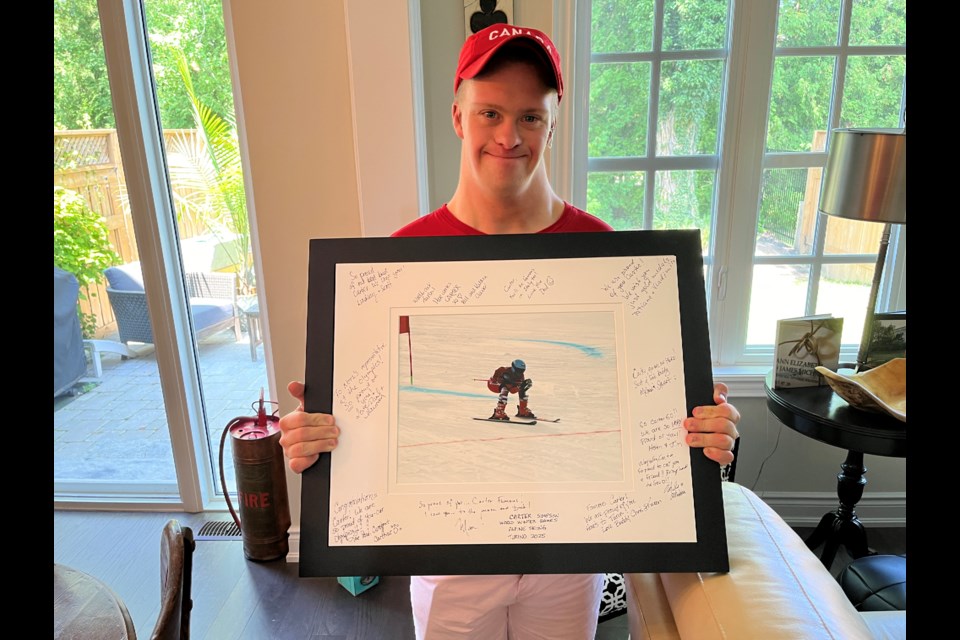 Carter Simpson holds up a framed photo of one of his races at the Nationals in March. The sides are adorned with congratulations from family and friends on his being named to Team Canada for the Worlds in 2025.