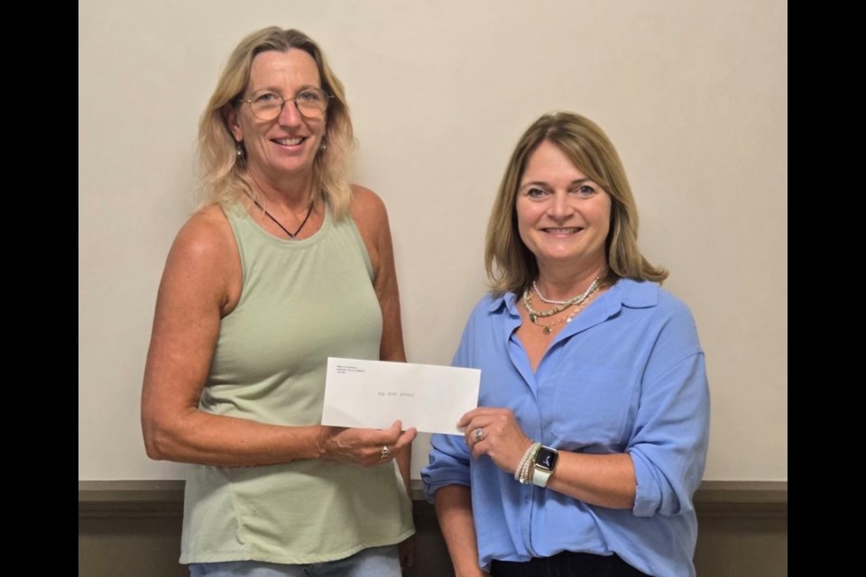 Steffanie Bjorgan, executive director of Red Roof Retreat, receives a cheque from Lisa Burland.
