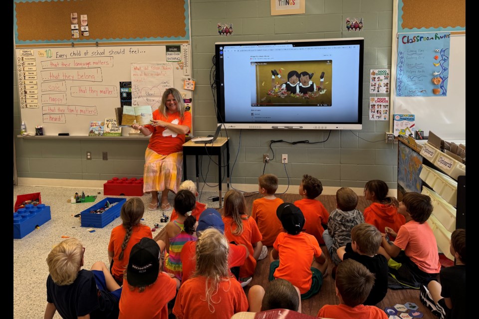 Grade 1 and 2 students in a Truth and Reconciliation class at Crossroads School listen to a read aloud of When We Were Alone, by David Alexander Robertson; a book about resilience, empowerment and strength.