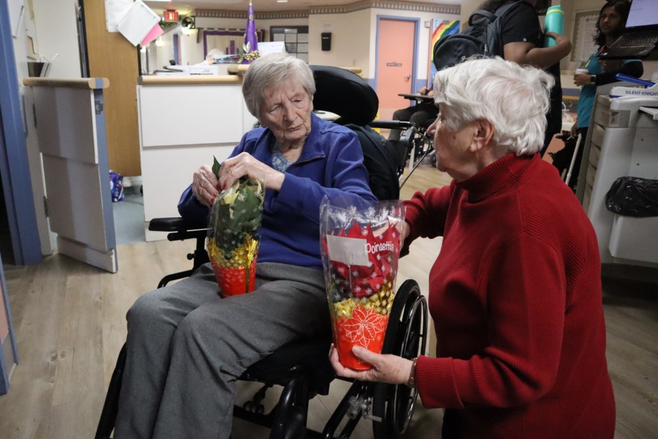 At Pleasant Manor, Frieda Neufeld accepts the first delivery of a poinsettia from volunteer Ingrid Regier.