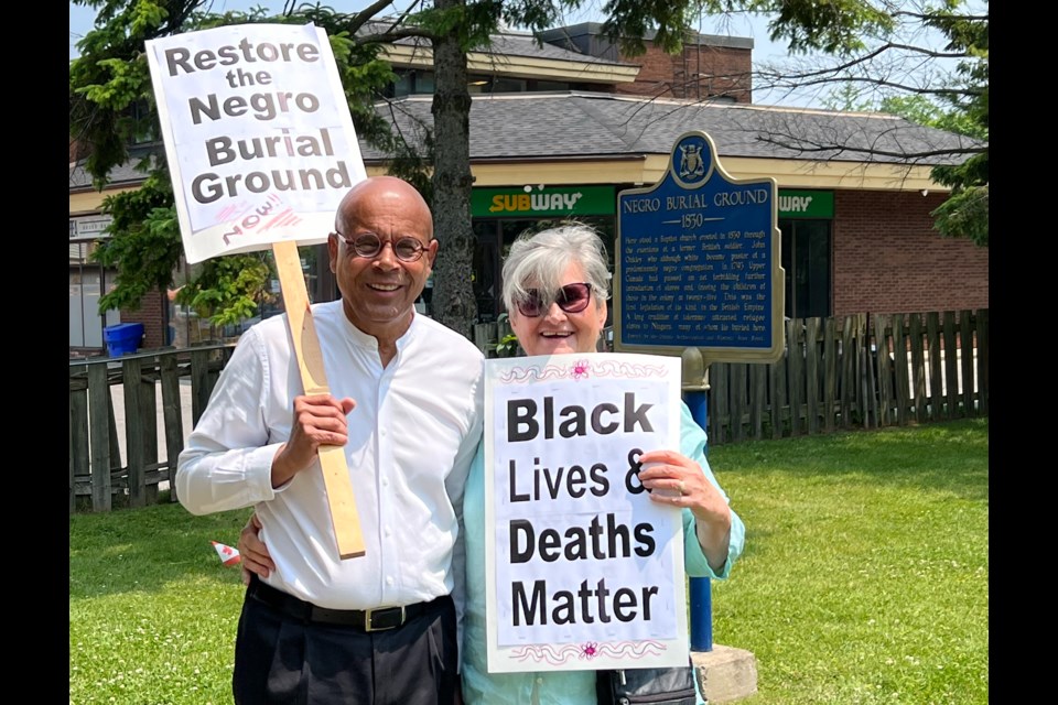 James Russell and his wife Marilyn at the Negro Burial Ground with their signs.