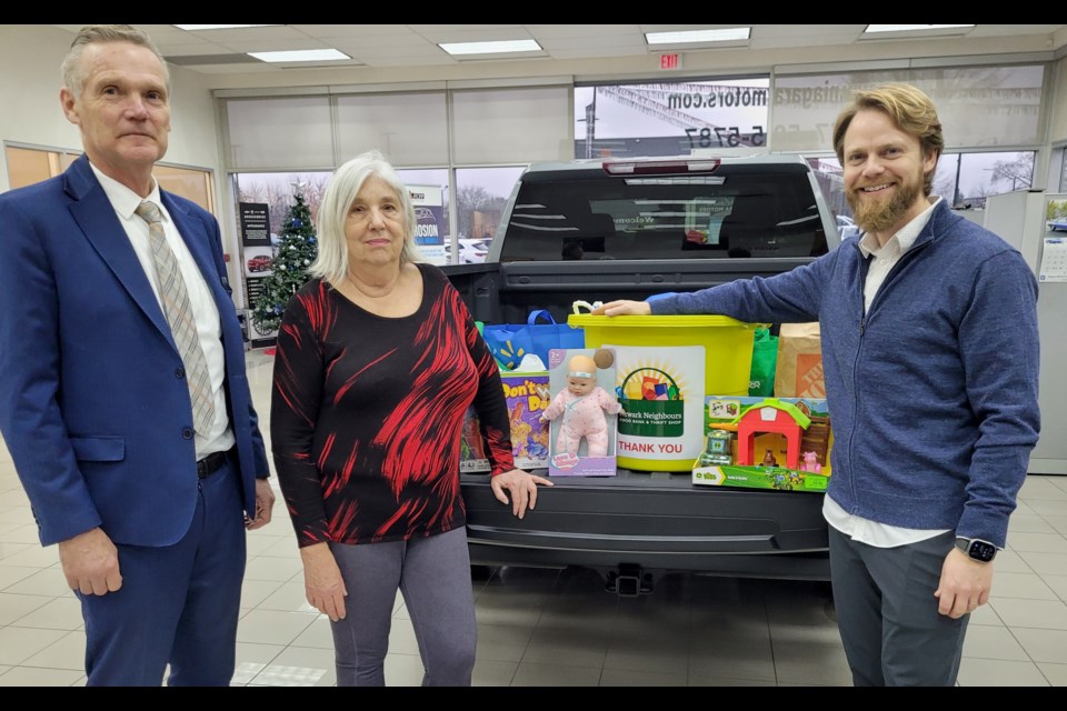 Dave Dick of Niagara Motors, Cindy Grant of Newark Neighbours and John Dick of Niagara Motors show off the food and toys that have been dropped off at the dealership in exchange for draw ballots that could win gift certificates or a big screen TV.