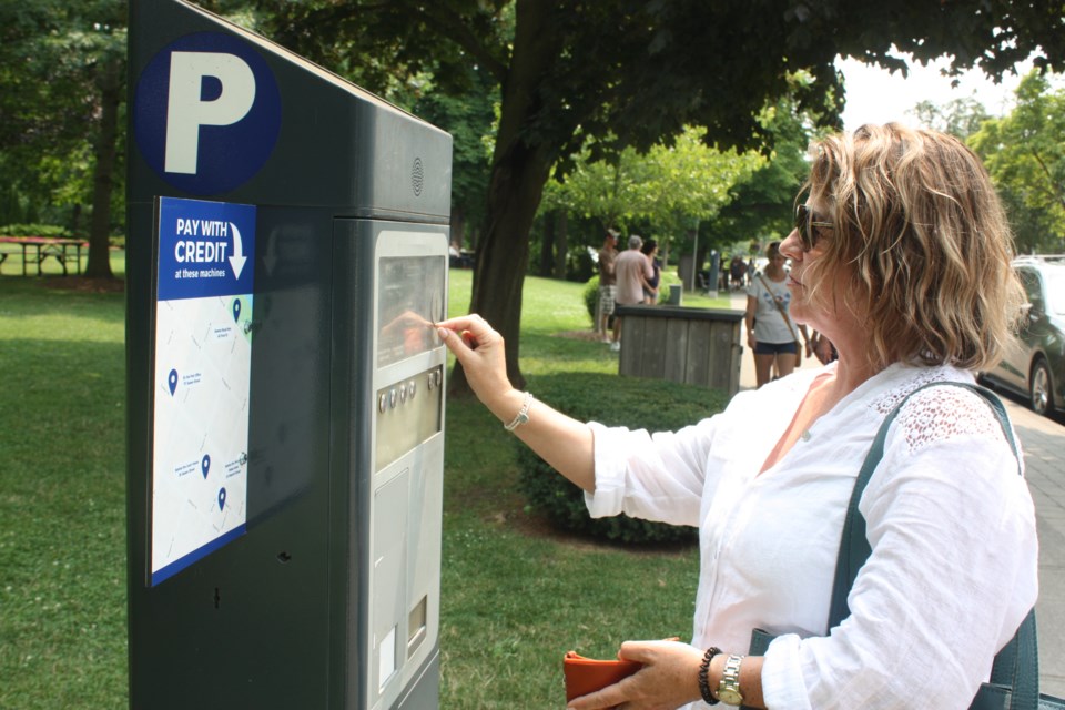 Barbara Hodge, a Montreal resident, pays for parking using coins in the Old Town Monday.