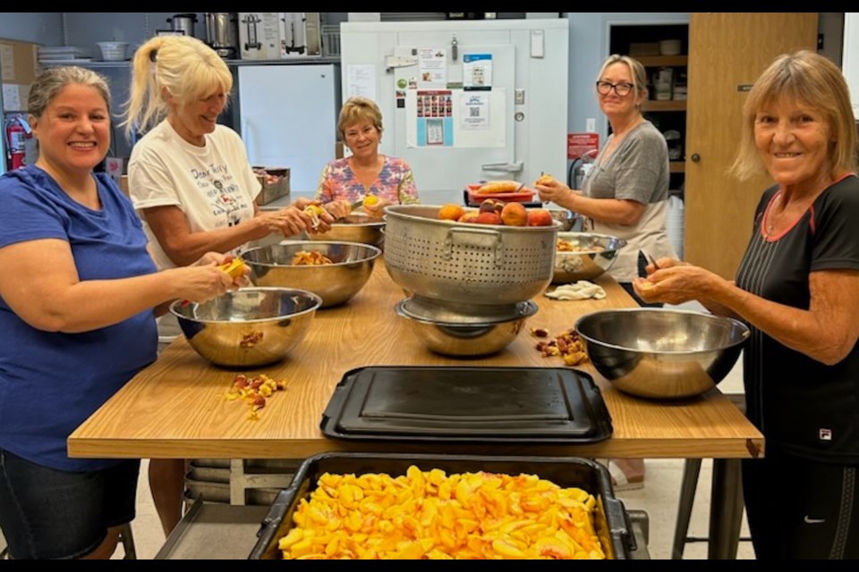 Connie Pillitteri, Joan King, Lynette McFarland, Karen Skeoch and Anna Kovacevic peeling and slicing peaches to fill 160 pies Tuesday. 