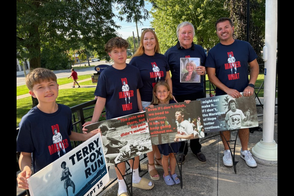 Sarah and Mike Pillitteri with Leo, Lucas Sophie, and Sarah's dad Dave Eke holding a photo of Debbie at the town hall when the Terry Fox flag was raised. They will be at Sunday's run, which is honouring Debbie. 