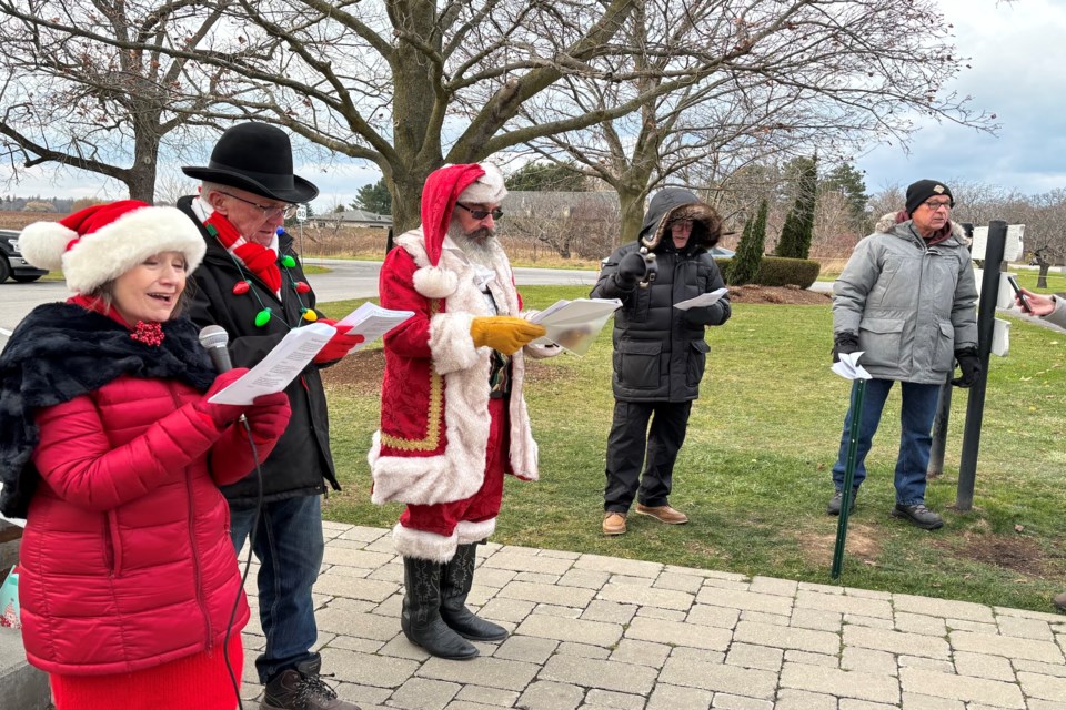 Dianne Ticknor and Rick Meloen are joined by town crier Tom Pekar for the Living Water Wayside Chapel carol sing-along Saturday.