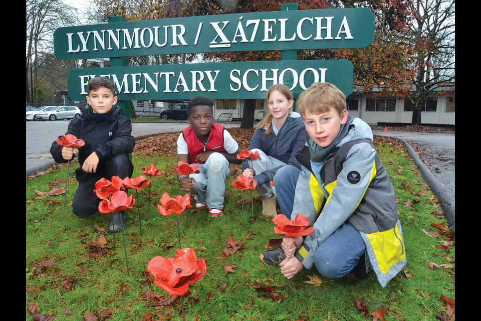 Lynnmour Elementary Grade 5 students Ronin Edwards, Samson Ligett, Ashlyn Nott and Reuben Hankinson plant their ceramic poppies commemorating Remembrance Day. Under the guidance of teacher Paul Best, students and staff created 310 clay poppies that they will plant at the school this week.