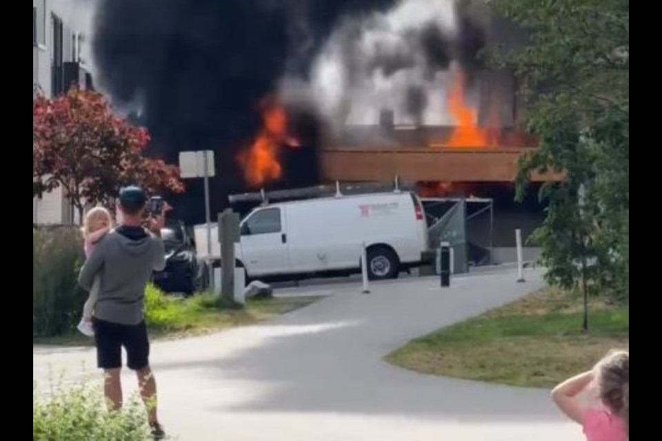 Flames and black smoke pour from The Morrison townhomes in North Vancouver on Wednesday evening.