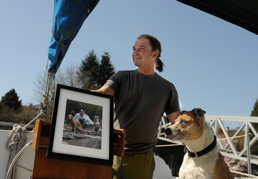 Matthew Witt and Rio on their family sailboat. Matthew holds a photo of his son Sebastian, who died after taking a toxic supply of fentanyl at age 20, on May 18, 2015. 