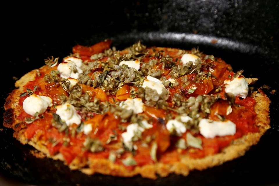 Nutrient-dense chick pea flour skillet pizza garnished with pickled holy basil blossoms. | Laura Marie Neubert 