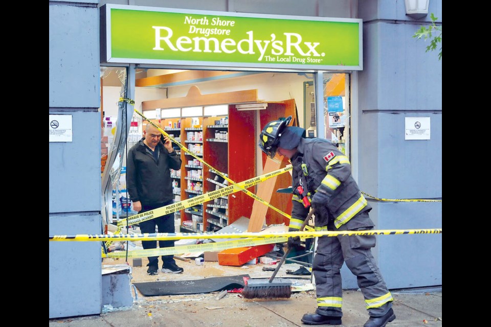 A City of North Vancouver firefighter cleans up debris after a driver crashed through the storefront of a pharmacy located on West 16th Street in North Vancouver, Oct. 4 / 2024. | Paul McGrath / North Shore ߣ 