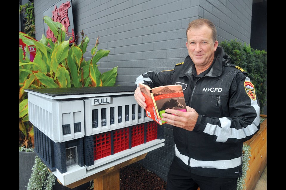 North Vancouver City Fire Department Deputy Chief David Owens makes use of the department’s new little library, which is modeled after the city’s fire hall. | Paul McGrath / North Shore News 