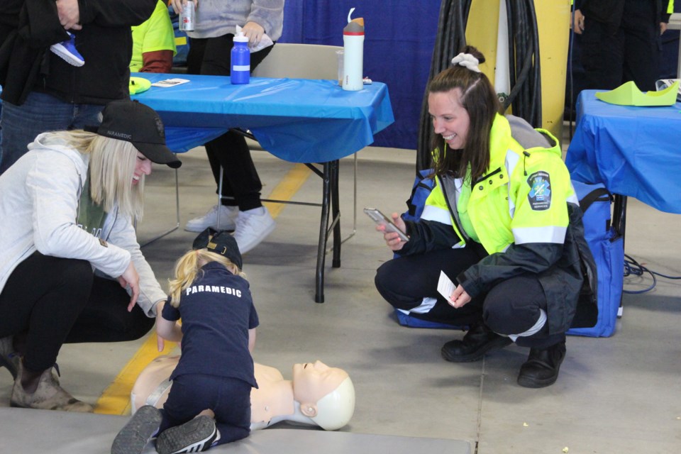 Paramedic and parent teaching little girl CPR
