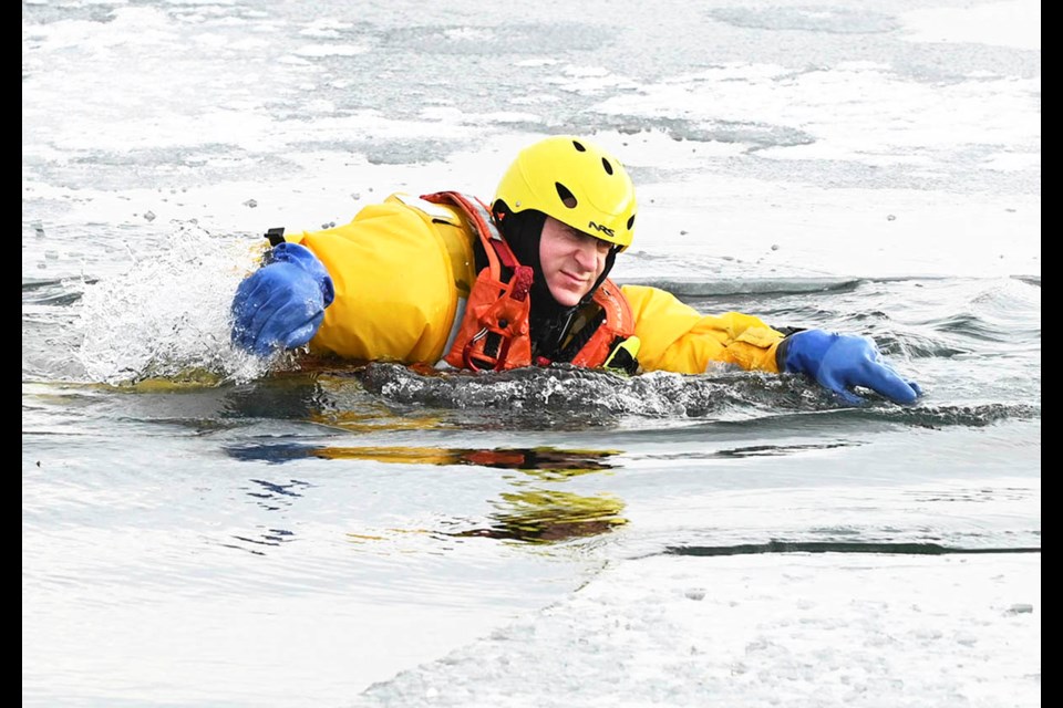 An Oakville firefighter/mock victim wearing a specialized ice rescue suit splashes in frigid lake water during ice rescue training at Bronte Outer Harbour.