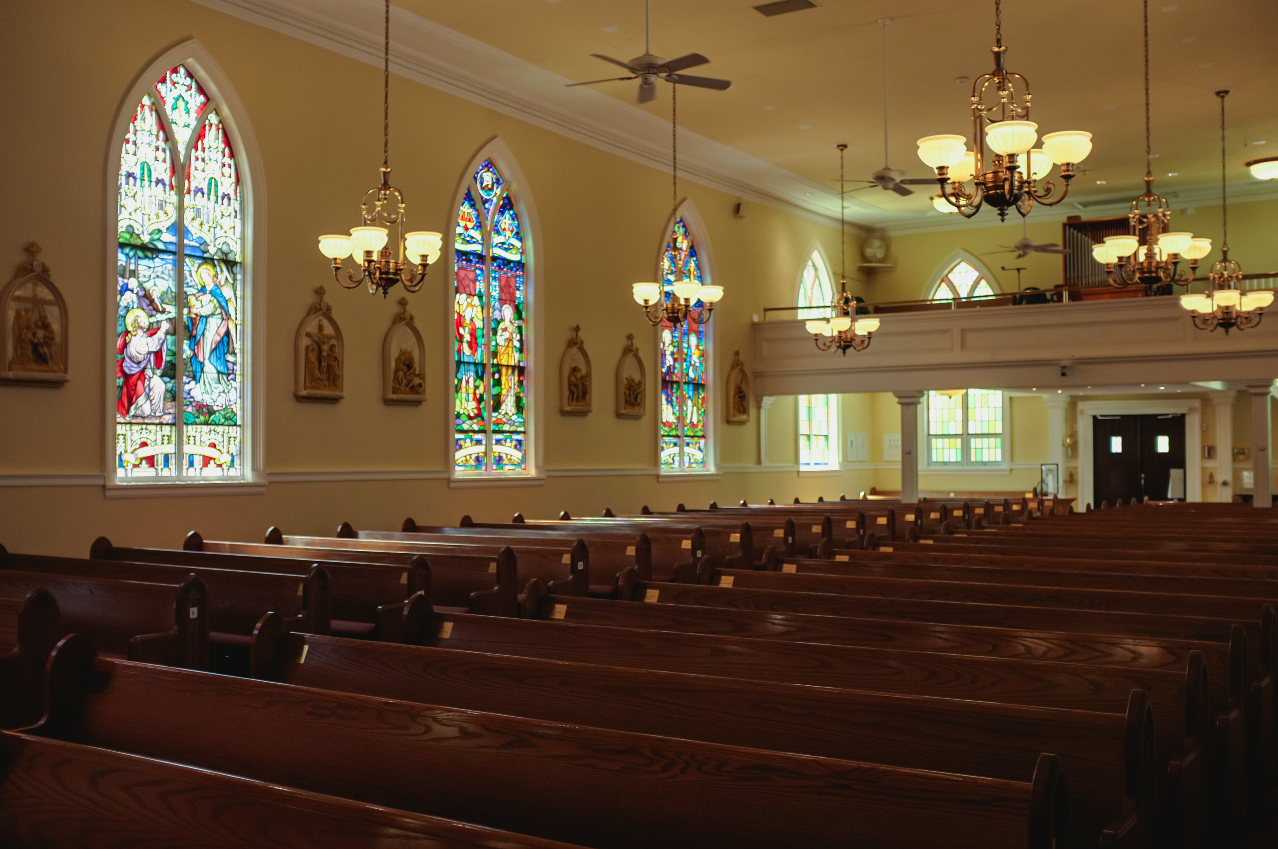 The stained glass windows of St. Andrews illuminate the rows of seats. | Mumin Mian