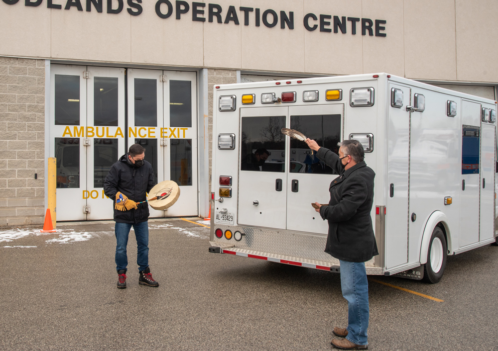 From left to right: Halton Region’s Indigenous Advisor Eddy Robinson and Local Indigenous Knowledge Keeper Stephen Paquette perform a blessing to the ambulance before it was donated to the Kenora Chiefs Advisory on December 17, 2020 at Woodlands Operations Centre. | Halton Region