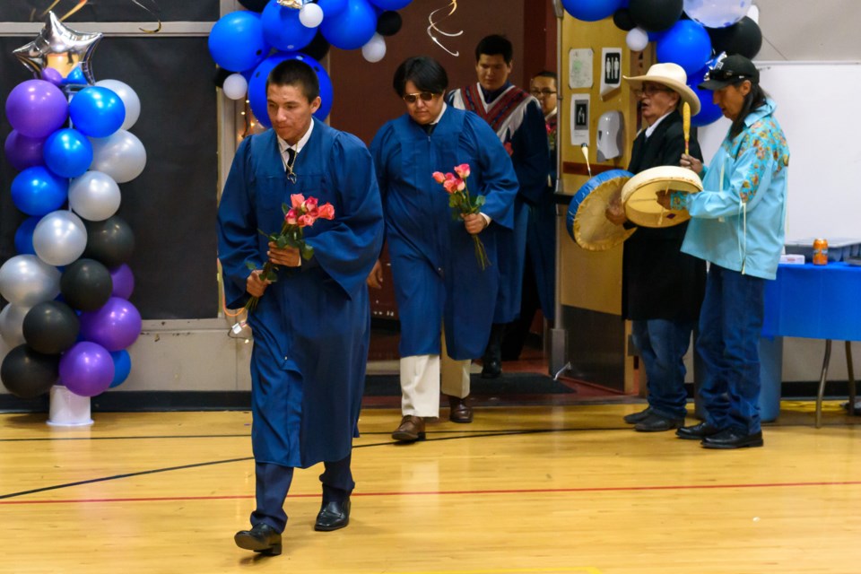 Mark Jaton Lefthand, front left, followed by Miguel Labelle, and Ezra Lefthand enter the gymnasium at Chief Jacob Bearspaw School in Eden Valley at the start of the formal graduation ceremony for the past three graduating classes on June 28.