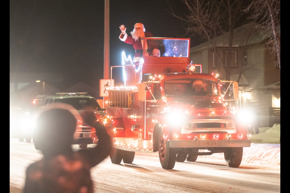 While giving his reindeer a much-needed break, Santa Claus gets an escort by the Okotoks Fire Dept., Municipal Enforcement, and RCMP riding atop a 1956 antique fire engine for the annual Christmas Eve Parade on Dec. 24. The tradition began over 20 years ago when Santa stopped by the Okotoks Fire Dept. asking for directions and got a tour from the fire department and the RCMP auxiliary.