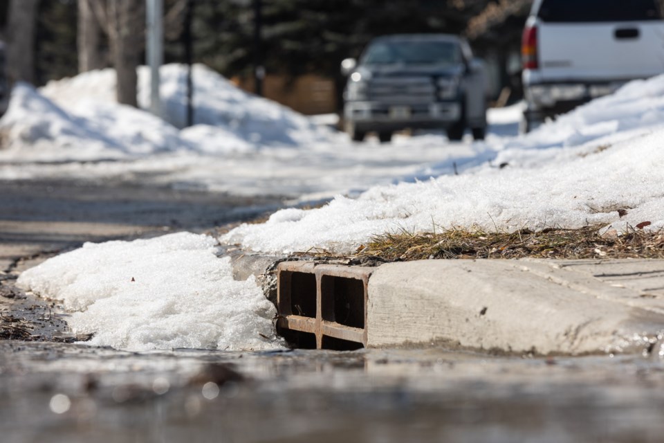 Water flows into a storm drain along Robinson Drive in Okotoks on March 25, 2023.