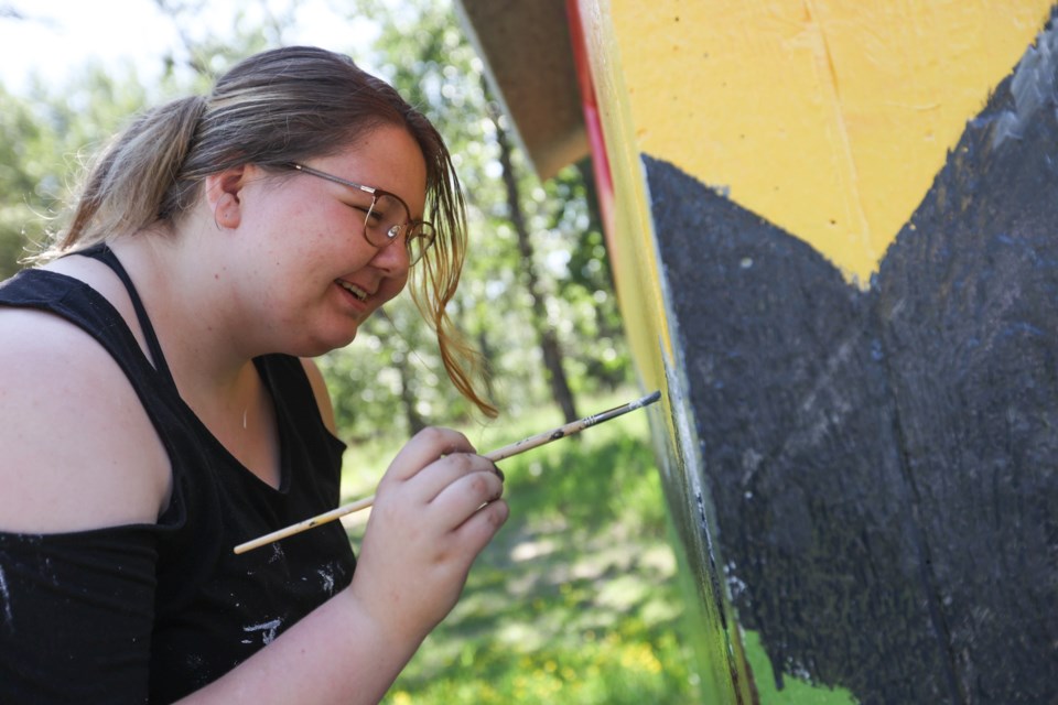 Alberta High School of Fine Arts grad Brooklyn Quinn paints one of the Town of Okotoks public restrooms on June 29. Her design was one of three chosen this year.