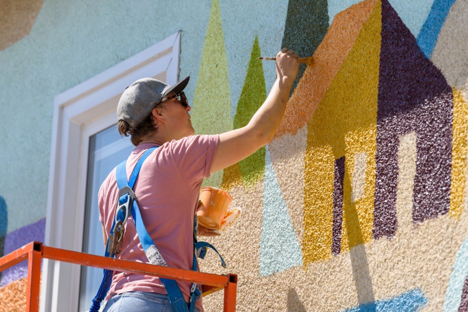 Artist Sarah Slaughter works on a mural on the east wall of the Elks Hall on Aug 1. Slaughter was commissioned by the Okotoks and District Chamber of Commerce to complete the mural as part of a “shop local” campaign.