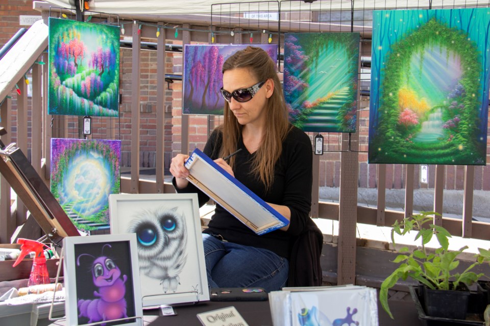 Natalie Von Raven works on a new painting in front of the Okotoks Art Gallery for the Art on the Lawn outdoor art sale, held on May 25.