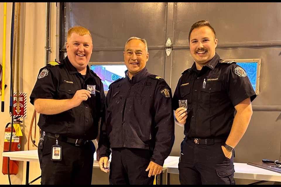 Fire Chief TJ Moore, left, and DVFR A/Lieut. Nick Warkman, right, recieve Challenge Coins from RCMP S/Sgt. Don Racette, centre, during an emergency services barbecue in Diamond Valley on June 17.