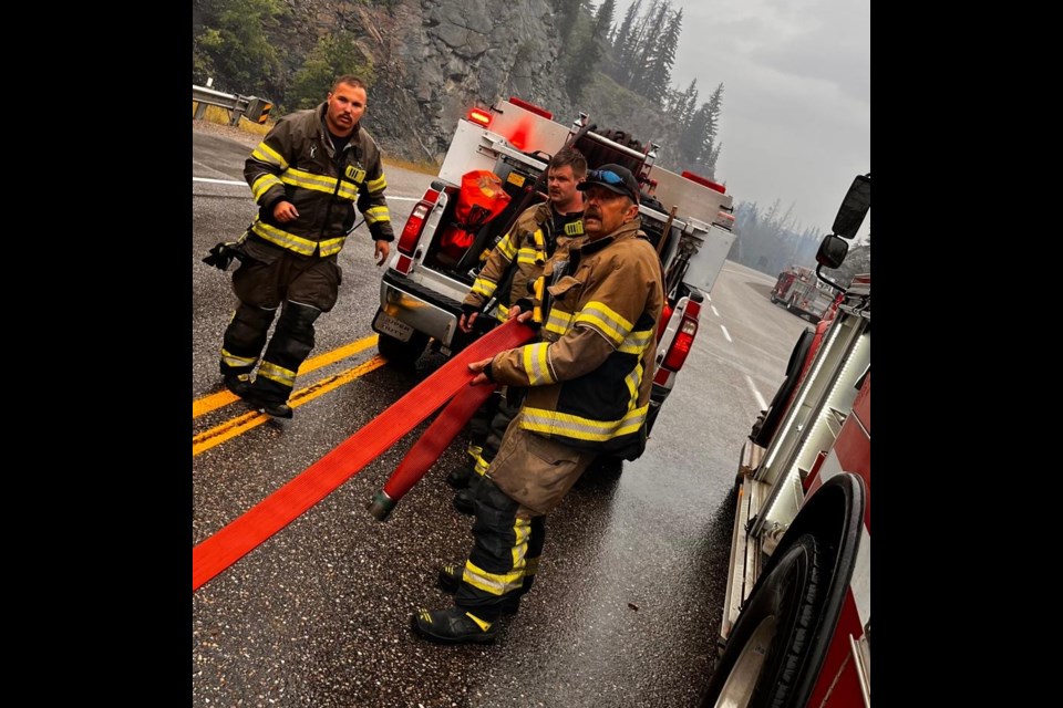 Diamond Valley Fire Rescue firefighters along Highway 16 at the bridge outside the town of Jasper, utilizing the Miette River as a fill point for their truck's water tanks on July 25. From left: Lt. Nicholas Warkman, Lt. Ethan Gardner and senior firefighter Jim Olien. 