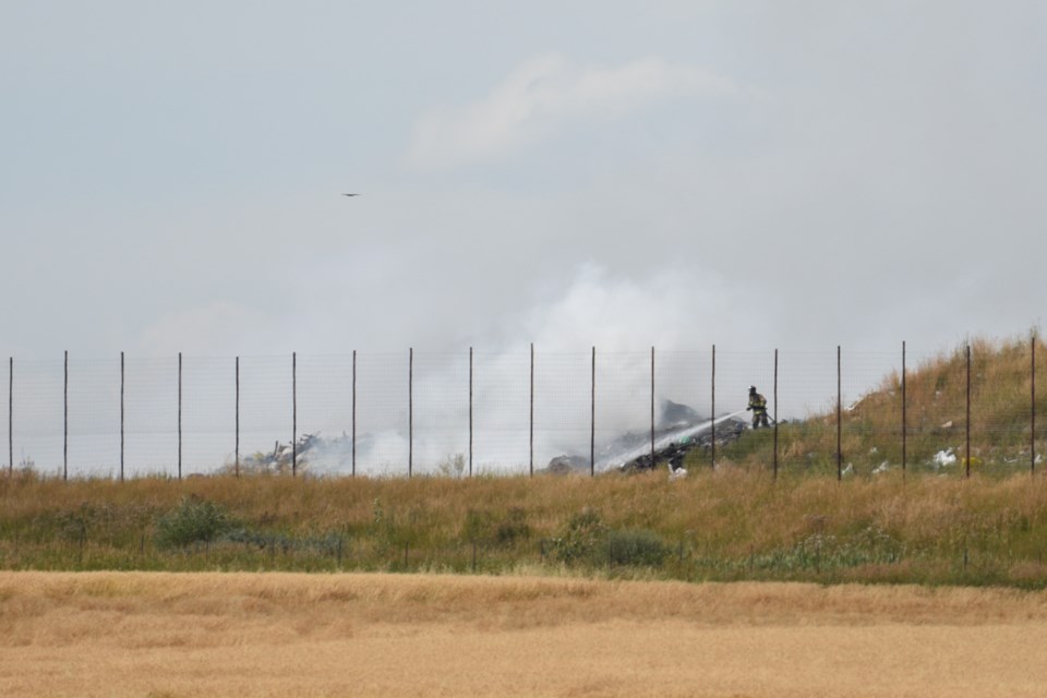 A firefighter hoses down a fire at the Foothills Regional Landfill south of Okotoks on Aug. 22.