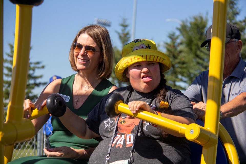 Mayor Tanya Thorn (left) and Madison Alger try out Okotoks' new wheelchair-accessible swing after it was unveiled at Bill Robertson Park on Sept. 5.