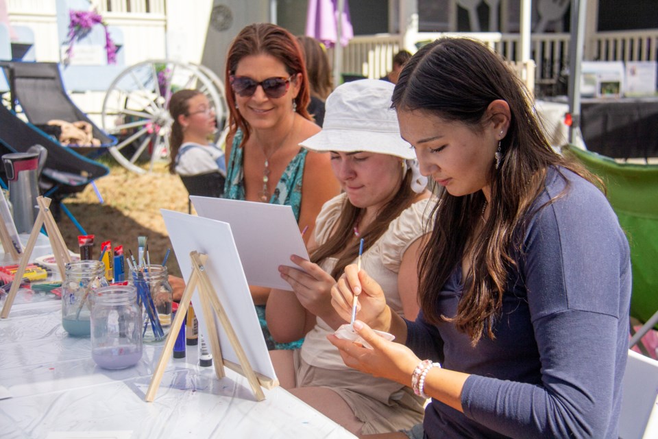 Local artists practice their craft at Okotoks ARTSwalk on Sept. 7. From left are Summer Day, Eva Friesen and Lily Kemp.