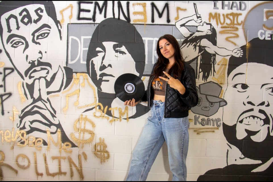 Artist Avenue owner Sarah Moore stands alongside the studio's new mural depicting prominent rappers on Sept. 6.