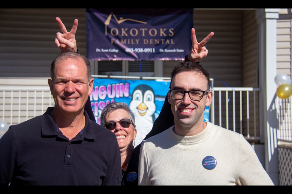 Okotoks Family Dental's Dr. Scott Gallup (left) and Dr. Kenneth Stairs are photobombed by dental assistant Heather Lunn at the dental clinic's first annual fundraiser on Sept. 21.