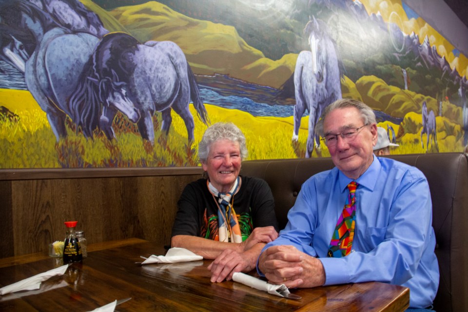 Artist Penny Corradine (left) and her partner Bill Faulkner pose under the Turner Inn Family Restaurant's 54-foot mural at the restaurant's grand opening party on Sept. 25 in Diamond Valley.