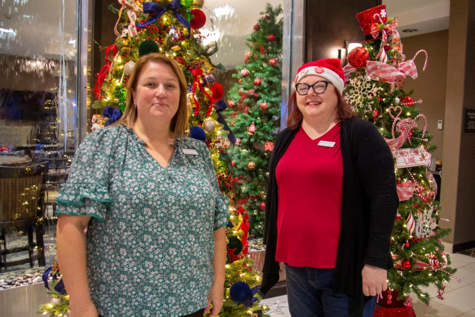 Sheep River Health Trust executive director Andrea Mitchell (left) and fund development and communications coordinator Christine Oakes pose with a couple Christmas trees at the Avenue of Trees 2024 launch party on Nov. 16.