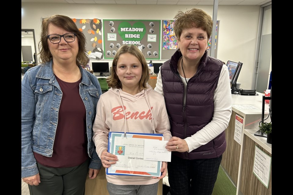 Foothills Writers Group members Dorothy Bentley (left) and Laurie Carmichael present Kira Cruikshank with her prizes. 