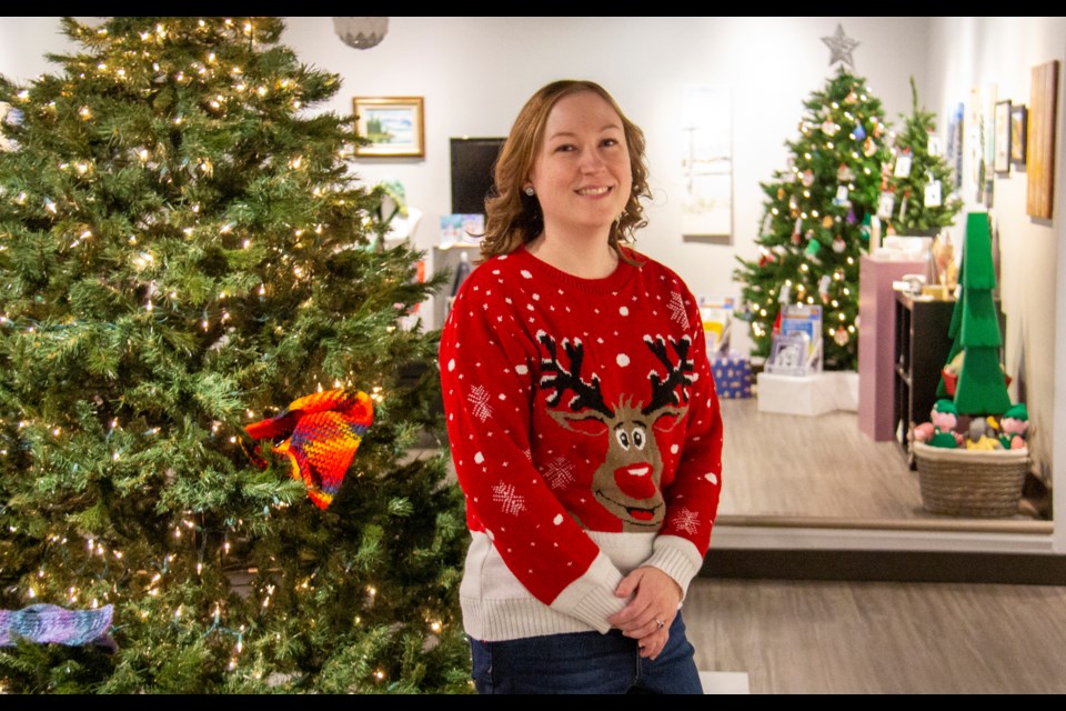 Gallery specialist Katrina Lougheed poses by the Tree of Warmth, part of the Spirit of Christmas showcase, in the Okotoks Art Gallery on Nov. 22.