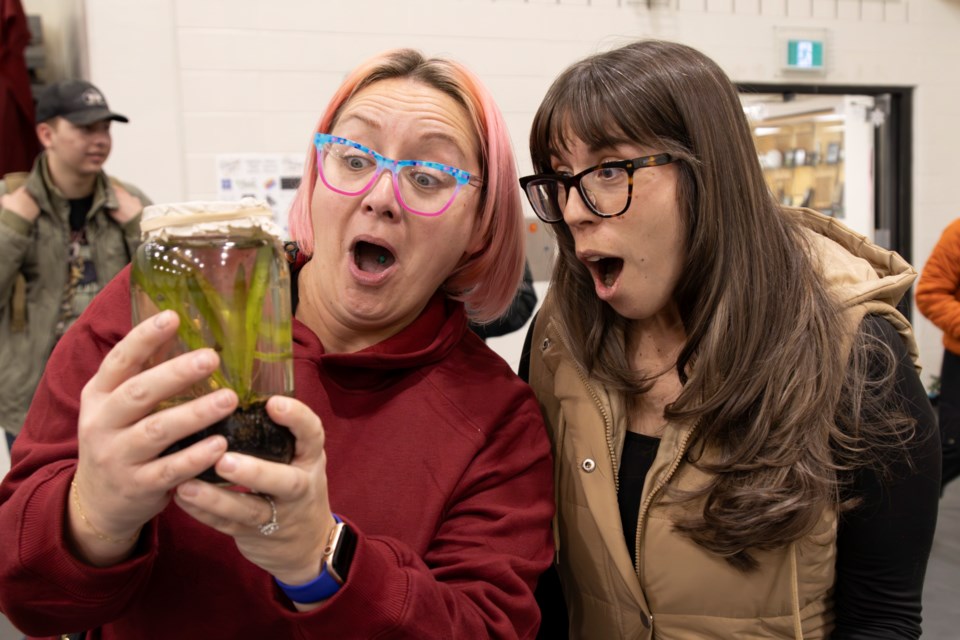 Kym Wilkie (left) and Marcie Rawson marvel at a pond in a jar during the Oilfields High School Winter Market in Diamond Valley on Dec. 5.