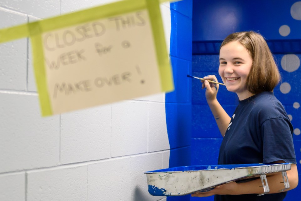 Grade 8 student Macy McKibbin paints a bathroom entrance at Okotoks Junior High on Dec. 6.