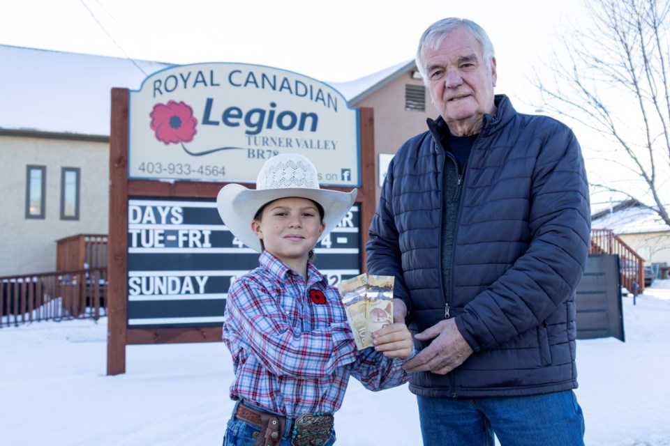 Paul Barton, president of the Turner Valley Legion, accepts a $200 donation from Casey Emerson on Dec. 5.