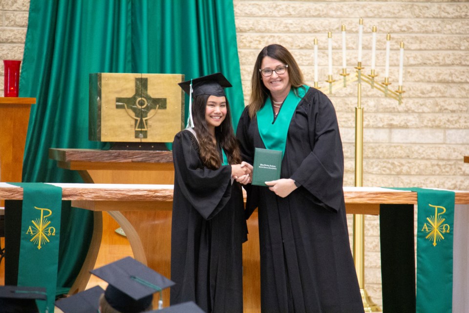 Eureka Mamaril receives her diploma from principal Diana Atkinson during the Holy Trinity Academy commencement ceremony on June 27 at St. James Church.