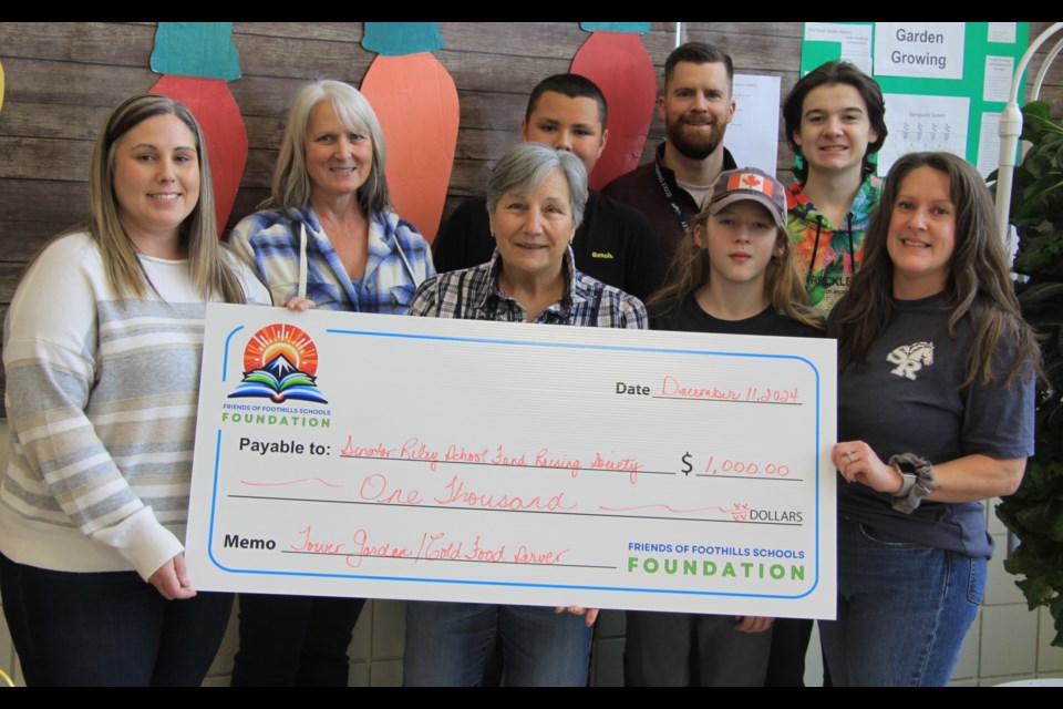 Friends of Foothills Schools Foundation executive director Marica Borovich-Law (middle) presents a cheque to École Senator Riley Middle School.