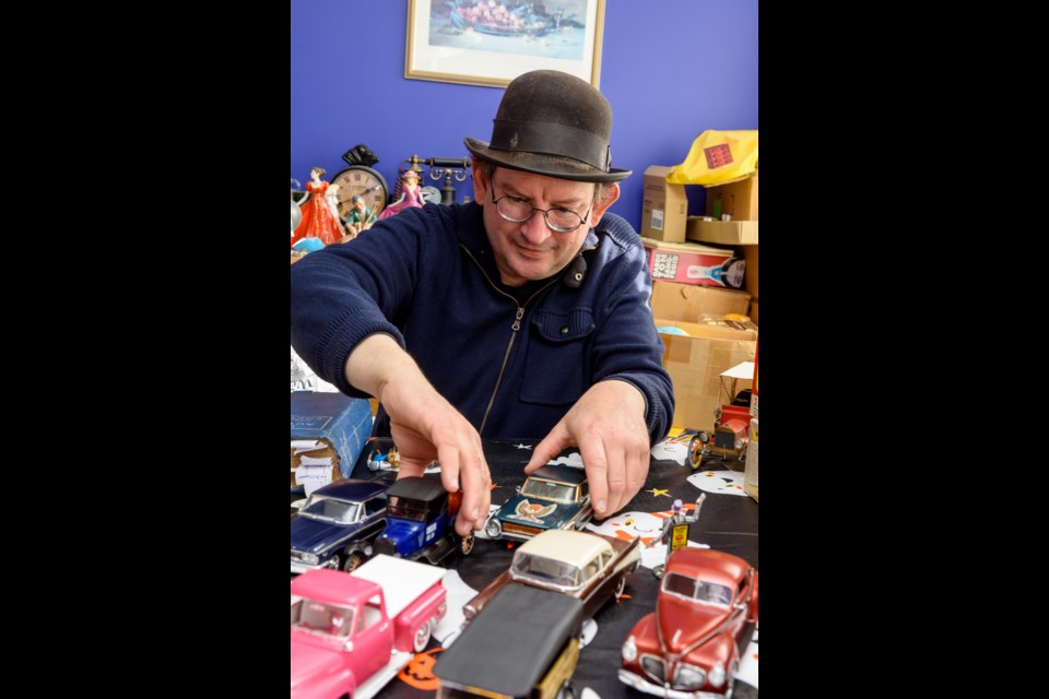 Trevor Ursulescu, an avid collector of model cars, arranges some of the vehicles for display in his home in High River.